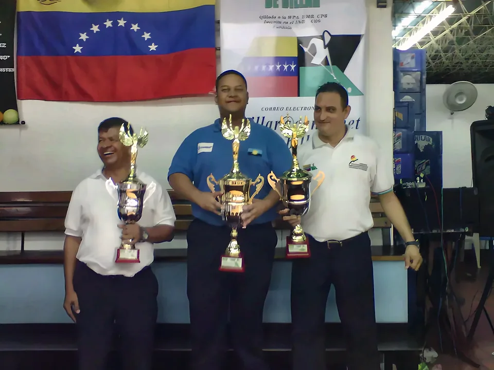 Premiación con trofeos ante la bandera de Venezuela y el pendón de la Federación.